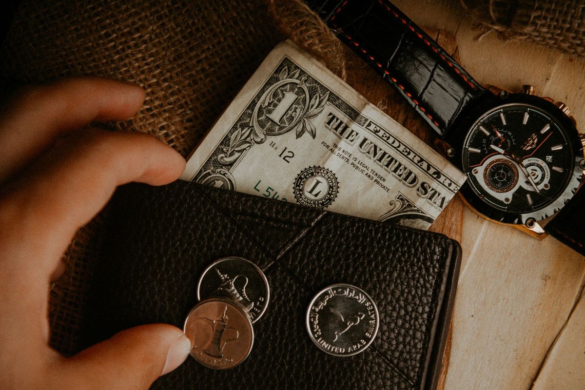 A detailed look at a wallet with money and a watch on a wooden surface