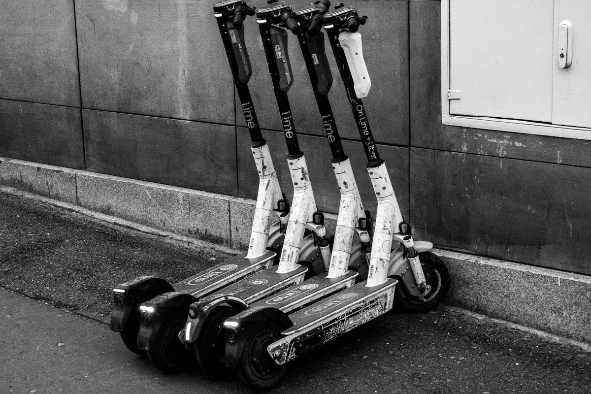 A group of electric scooters parked against a building wall