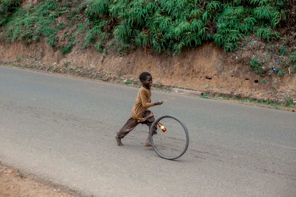 A happy boy plays with a wheel on a rural road
