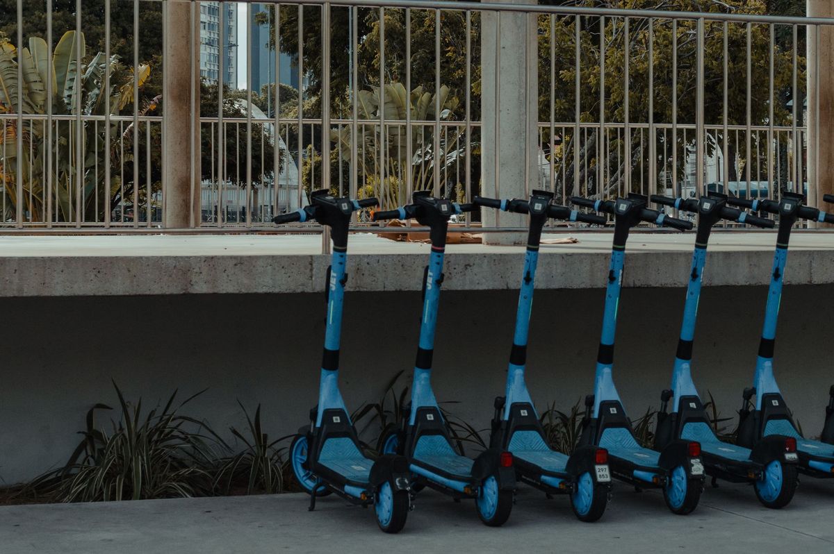 A line of blue electric scooters parked outdoors