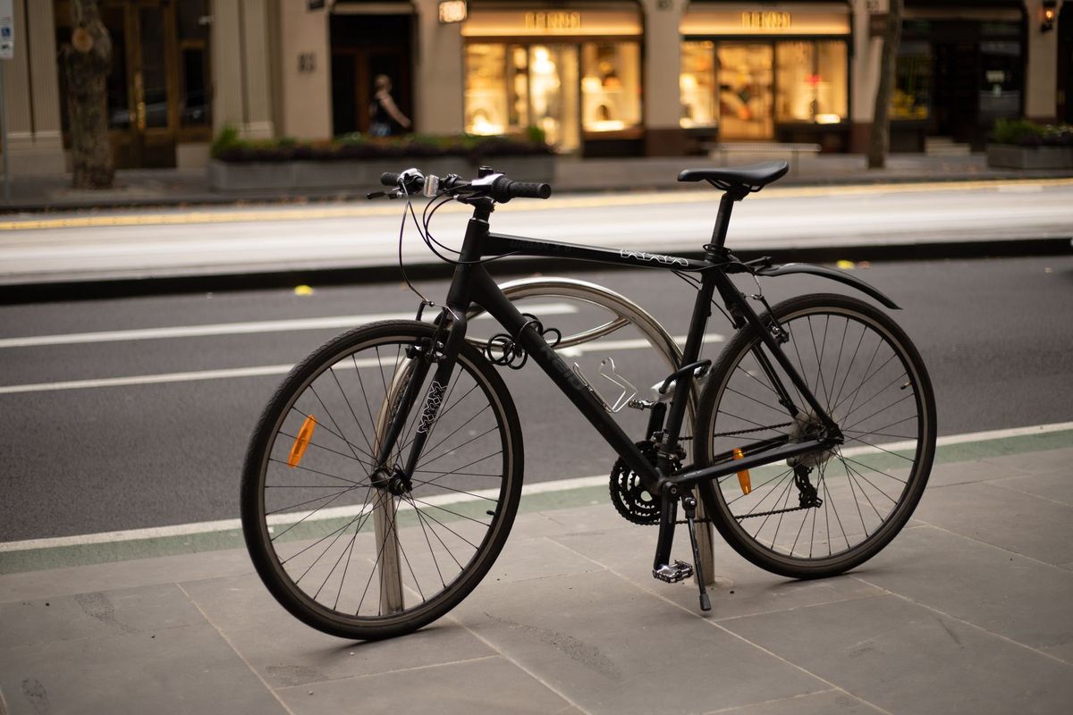 A modern road bike parked beside a busy city street on a smooth sidewalk