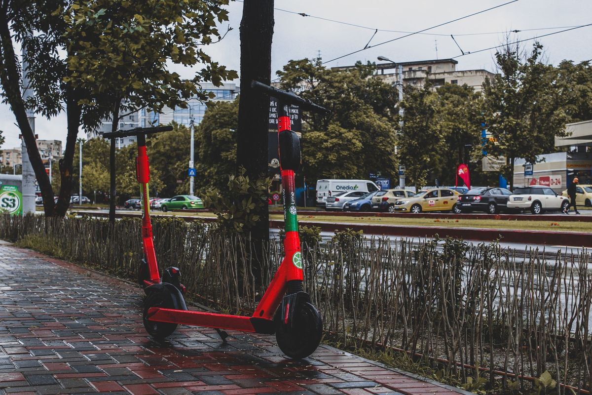 A vibrant red electric scooter parked on a wet sidewalk in Bucharest