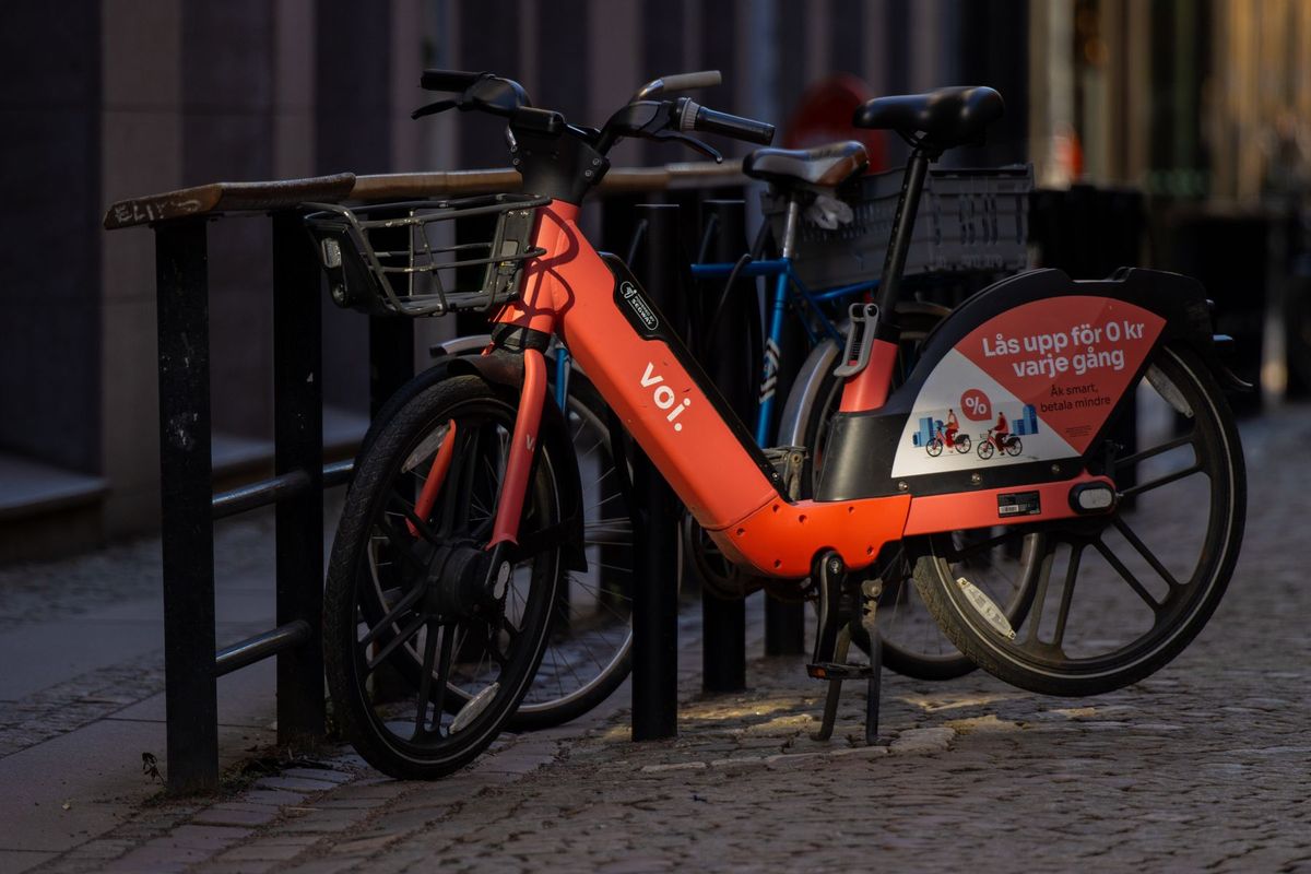 A Voi electric scooter parked on a cobblestone street in Gothenburg, Sweden, illuminated by evening light