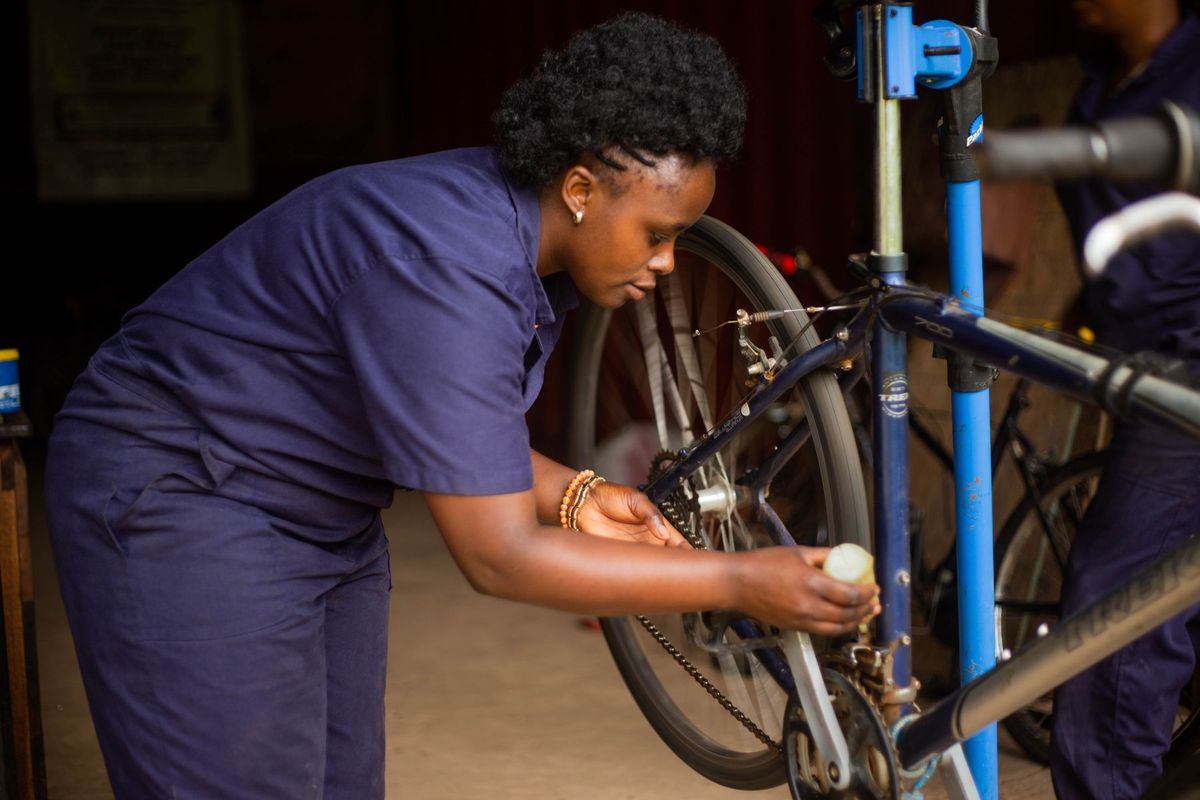 Adult female mechanic meticulously repairing a bicycle in a workshop setting