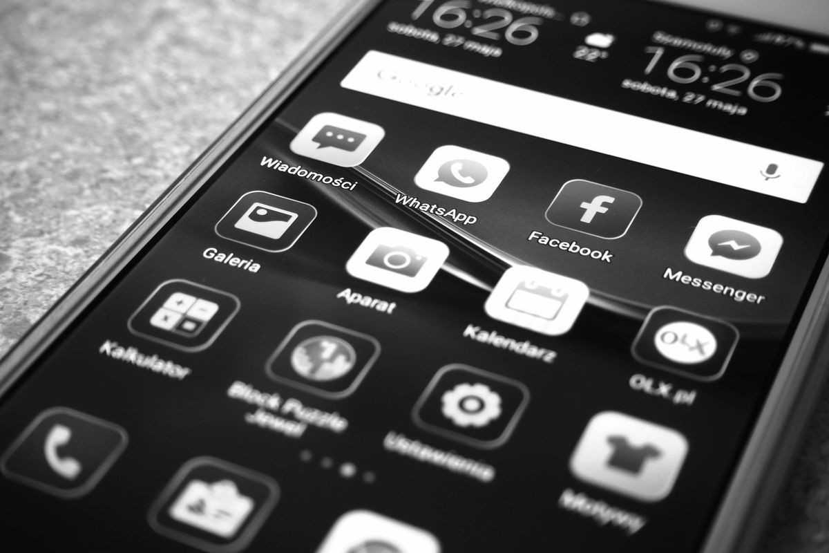 Black and white photo of smartphone showing popular app icons like Facebook and WhatsApp