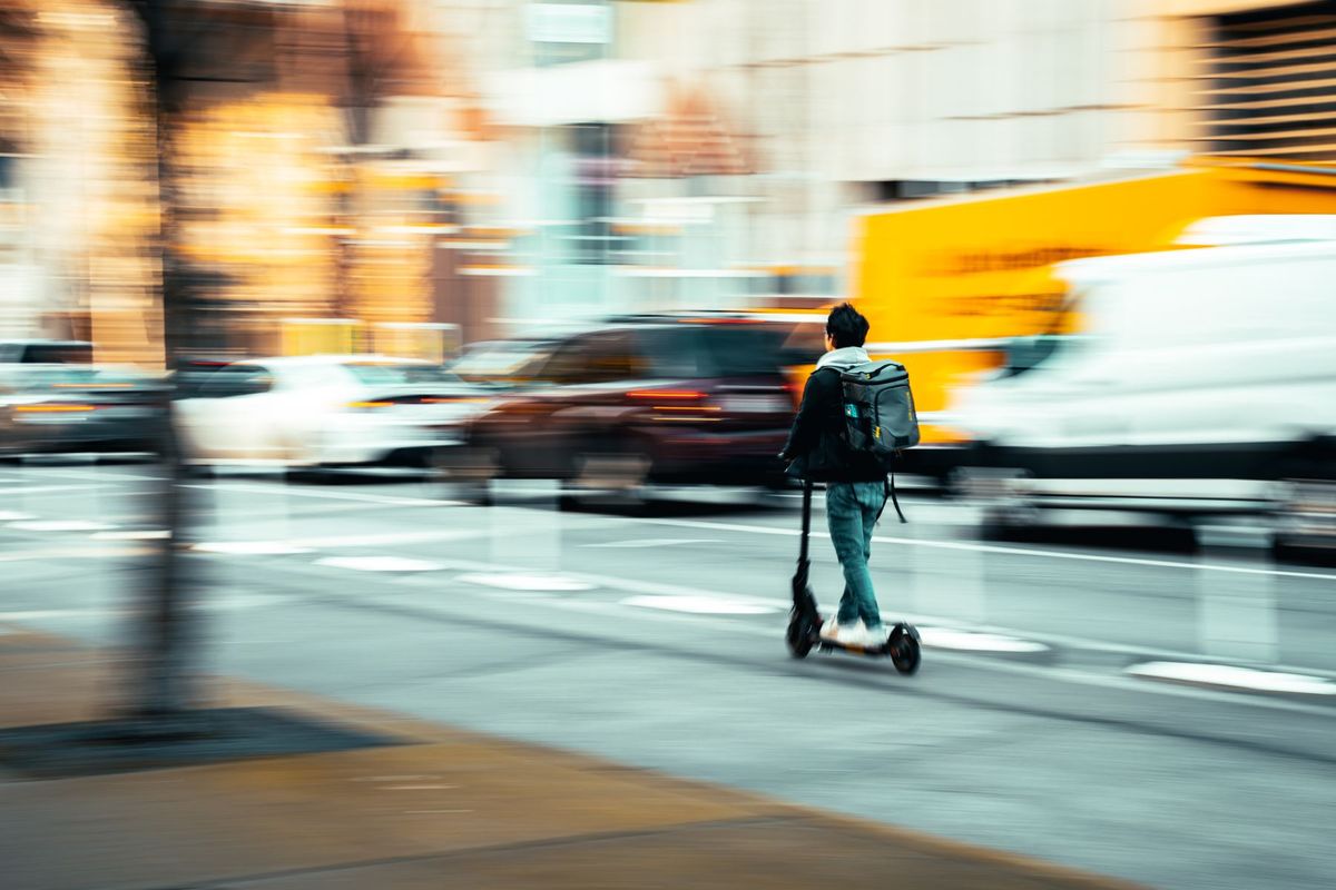 Blurred street scene in Seattle capturing swift movement of a scooter commuter amidst busy traffic
