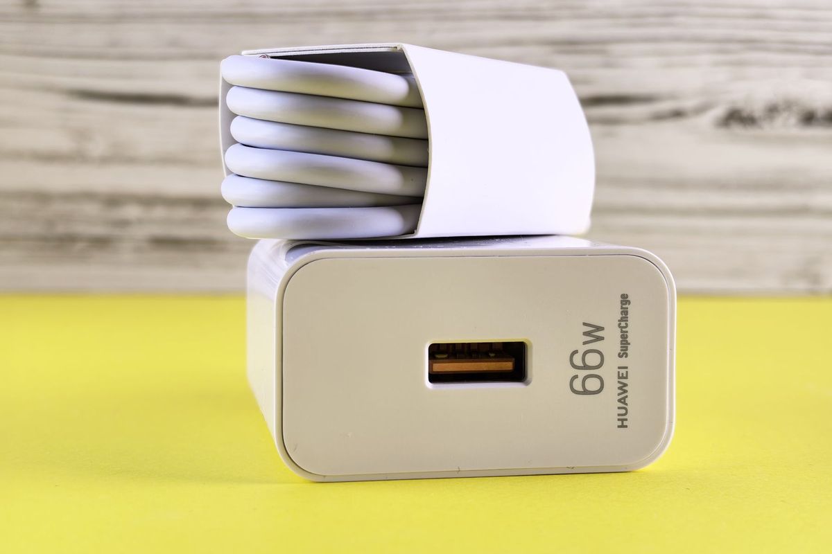 Close-up of 66W USB charger with coiled cable on a vibrant yellow surface