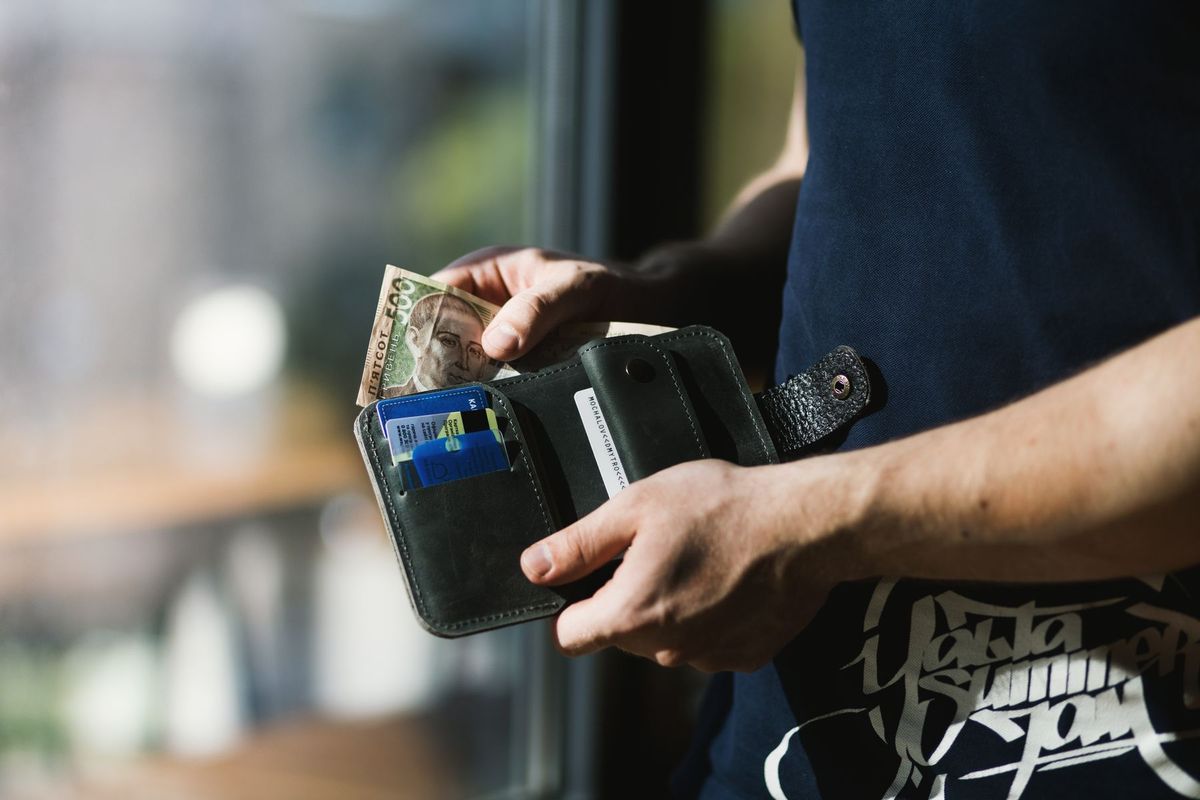 Close-up of a man holding a wallet with cash and credit cards, indoors