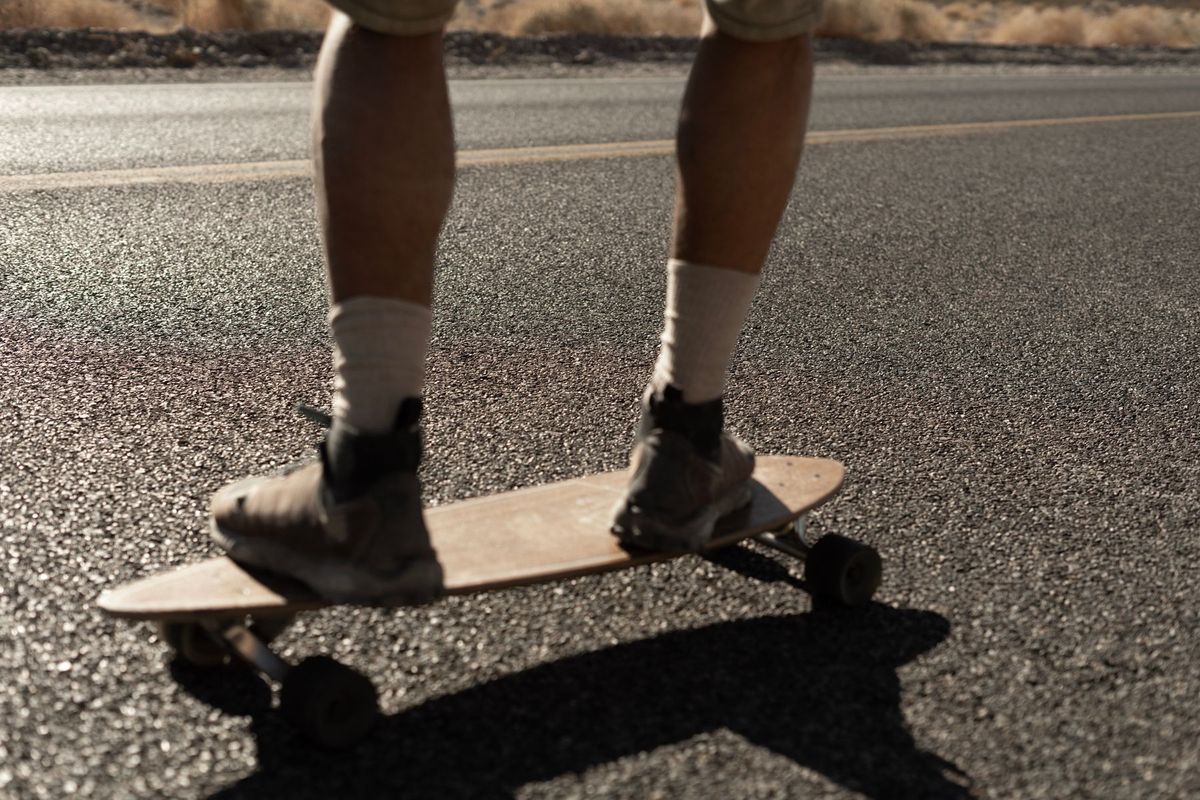 Close-up of a person skateboarding on a sunny road, enjoying an outdoor adventure
