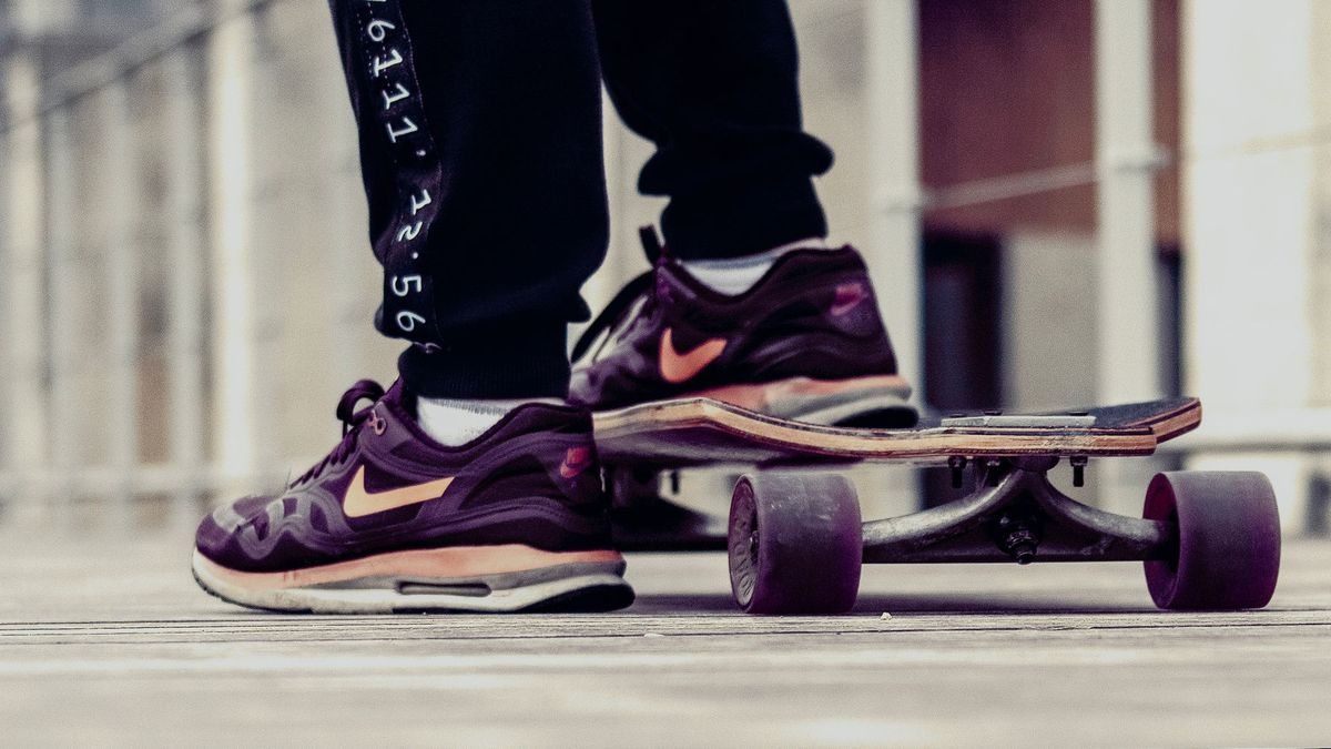 Close-up of a skateboarder in Nike sneakers on a wooden deck outdoors