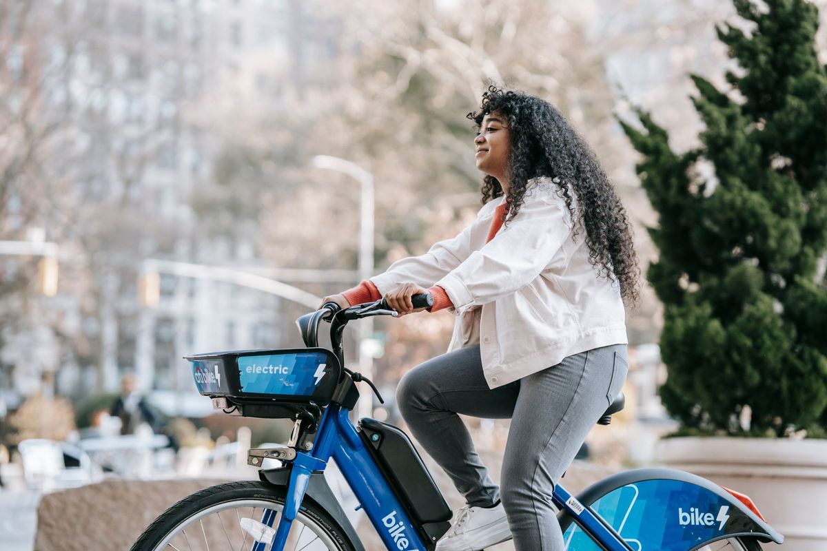 Confident young woman enjoying a peaceful ride on an electric bike in a vibrant urban setting