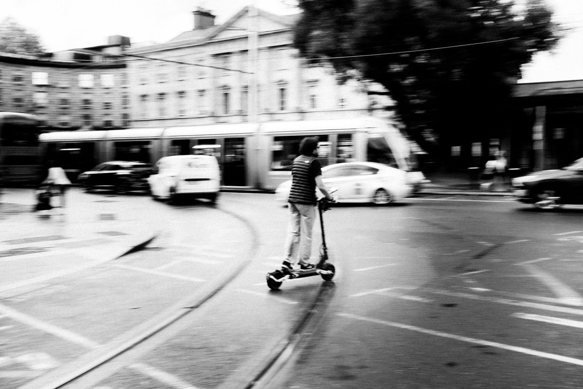 Dynamic black and white photo of a scooter rider navigating city streets in Dublin, Ireland