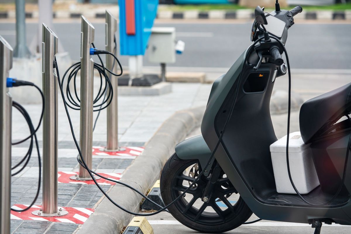 Electric scooter plugged into a charging station in a city environment