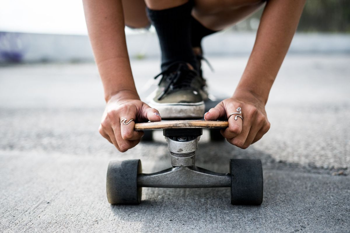 Focused shot of a skater crouching with a longboard on a concrete surface. Ideal for urban lifestyle concepts