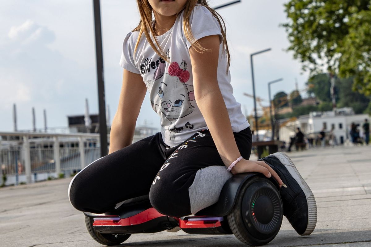 Girl kneeling on a hoverboard outdoors