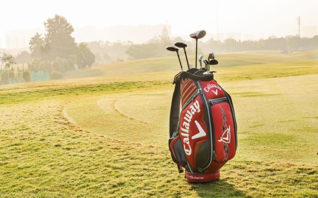 Golf bag and clubs on a sunny golf course with green grass