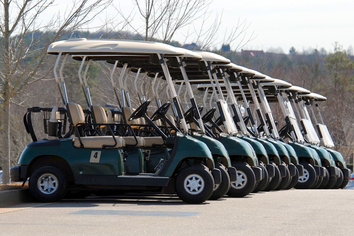 Golf carts parked in a row on a golf course under a clear sky