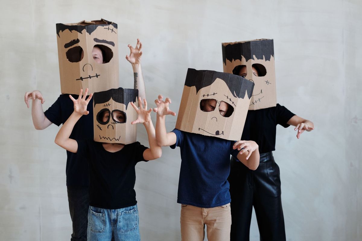 Group of children in DIY cardboard ghost costumes posing playfully for Halloween
