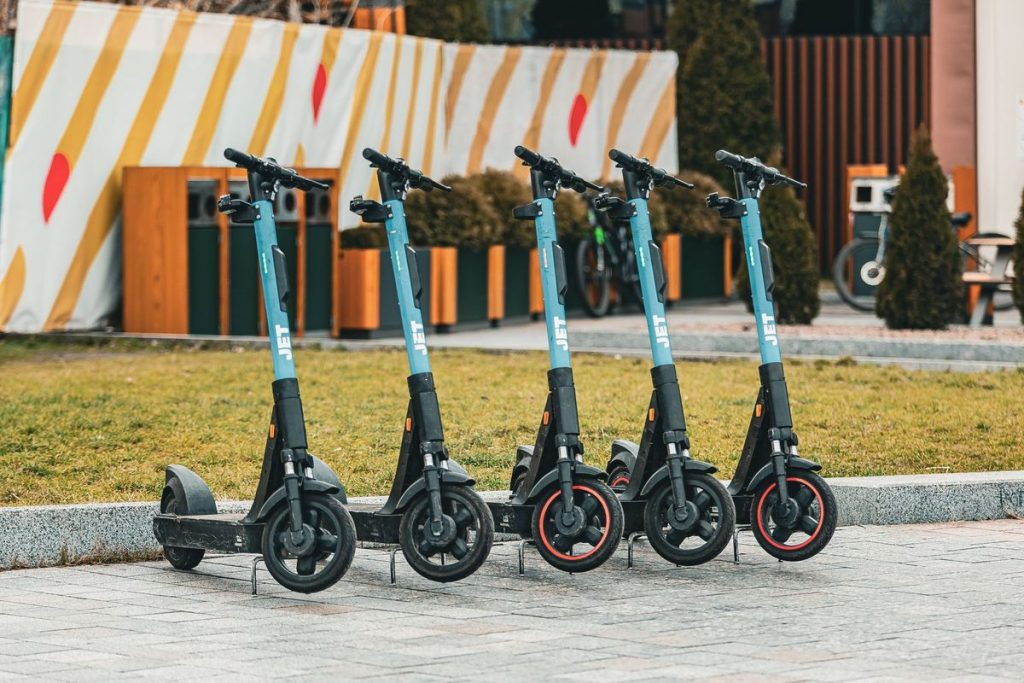 Group of five electric scooters neatly lined up outdoors, ready for rental use