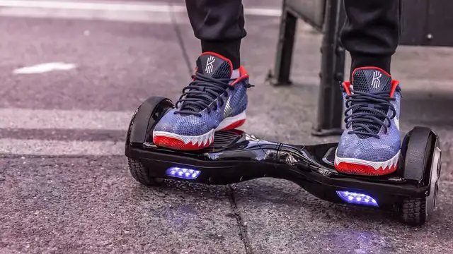 Close-up of a black hoverboard with blue LED wheel lights on a city street