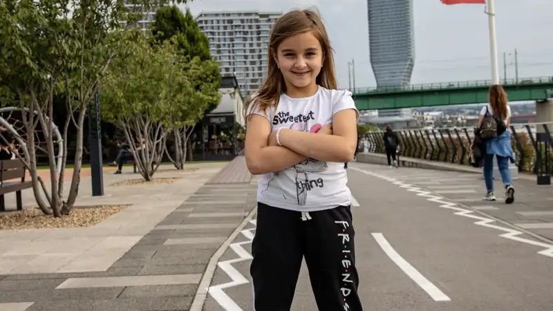 A young rider standing on a hoverboard on a paved park path
