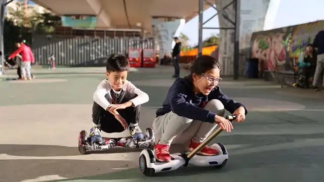 Two children with a hoverboard fitted to a go-kart attachment under a bridge