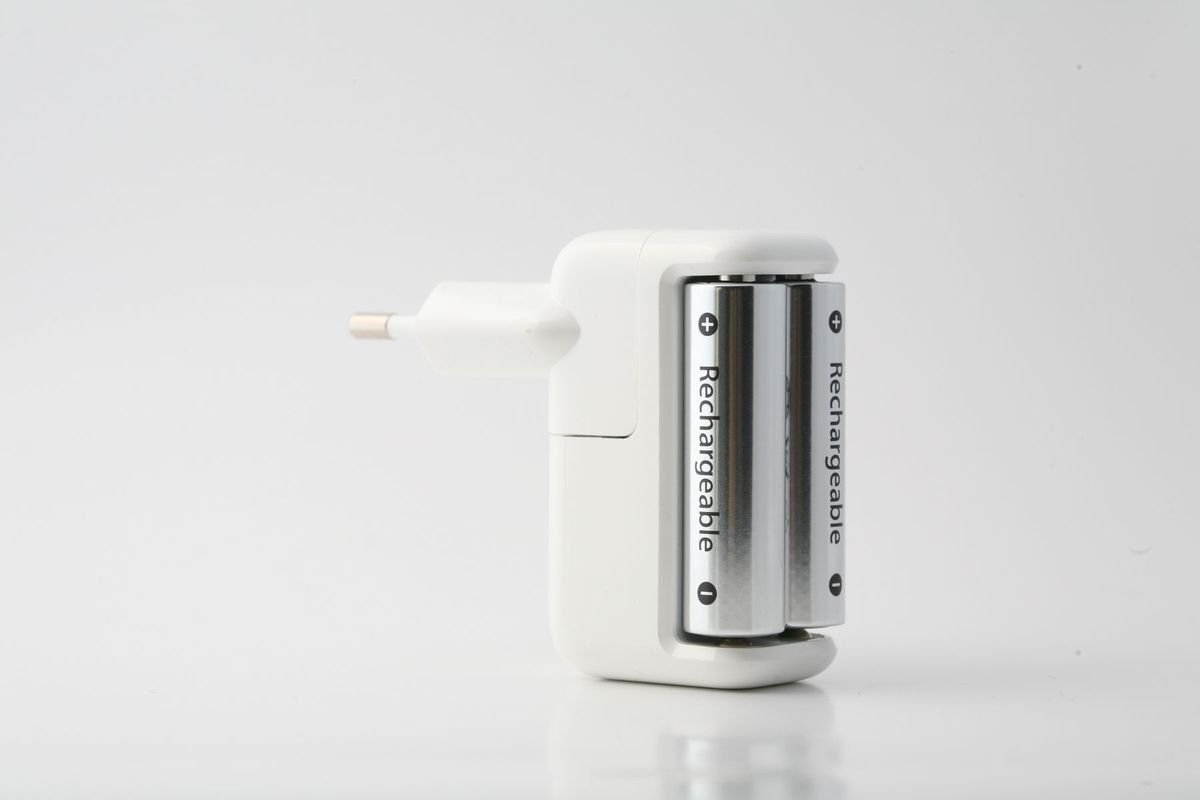 Minimalist shot of a rechargeable battery charger with two batteries on a white backdrop