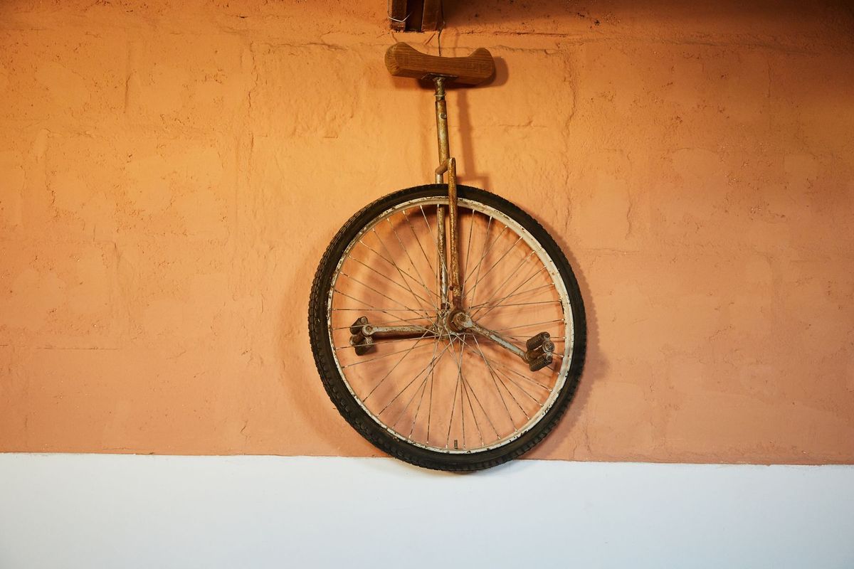 Rusty unicycle hangs as unique decor on orange brick wall indoors. Vintage and nostalgic vibe