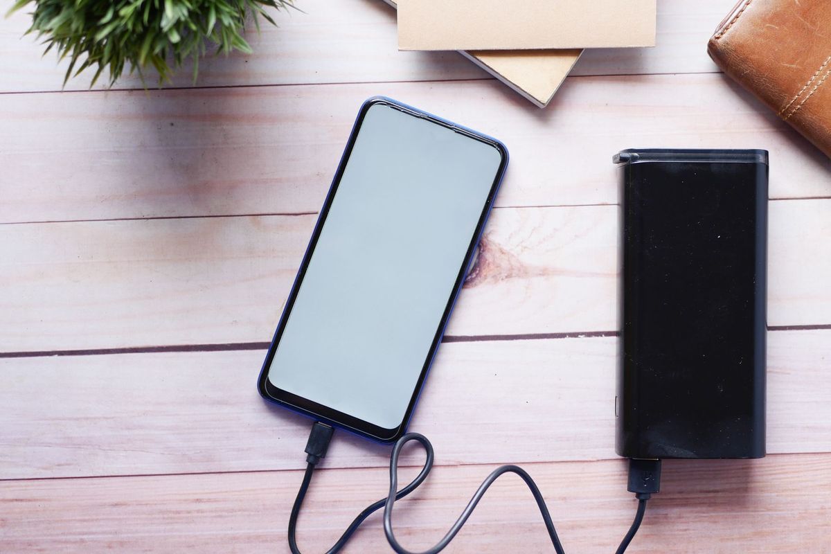 Smartphone charging with a power bank on a wooden desk