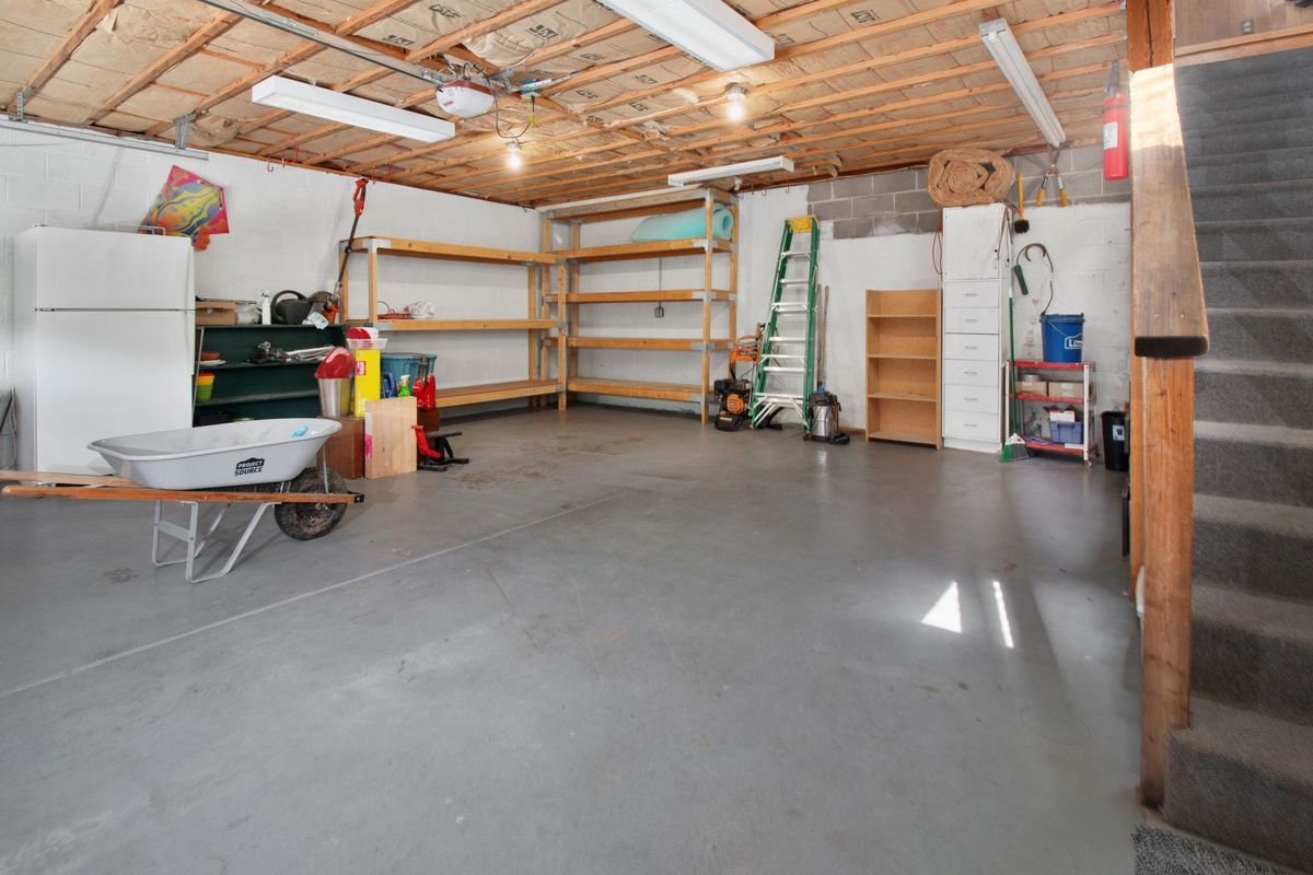 Spacious garage interior with storage shelves, tools, and a wheelbarrow