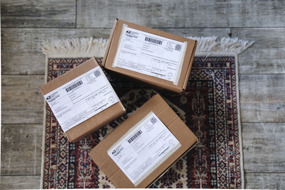 Three labeled delivery boxes placed on a decorative rug over a wooden floor
