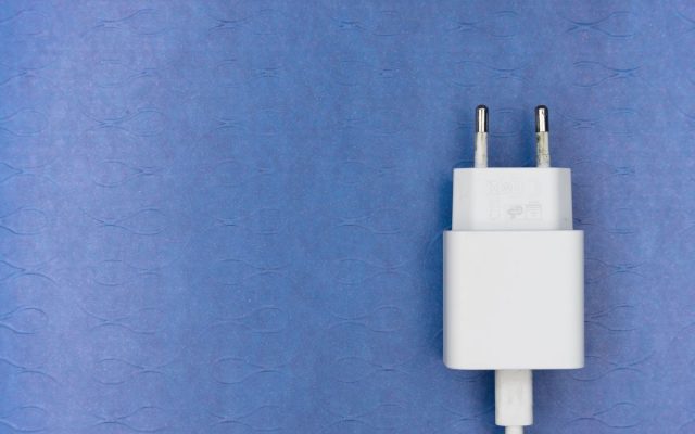 White electric charger plug on a blue textured surface