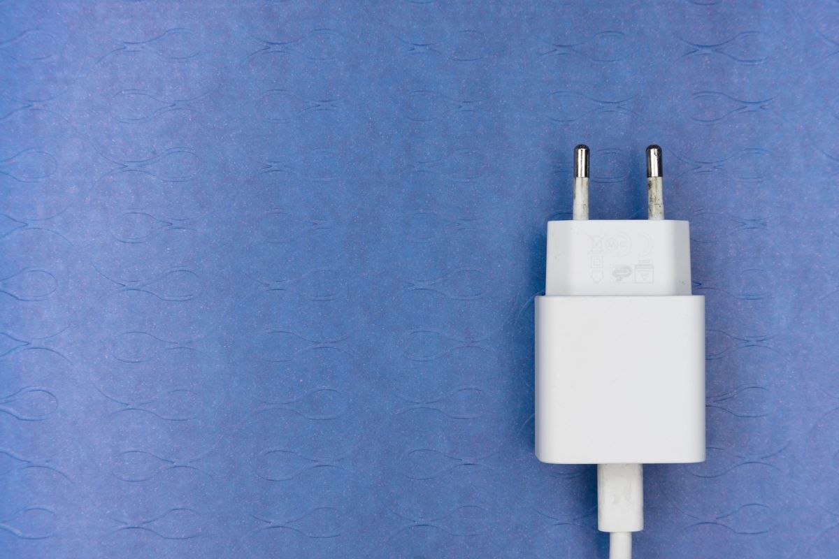 White electric charger plug on a blue textured surface