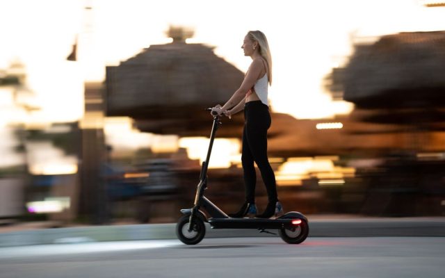 Woman enjoying an evening ride on an electric scooter with motion blur capturing speed and excitement