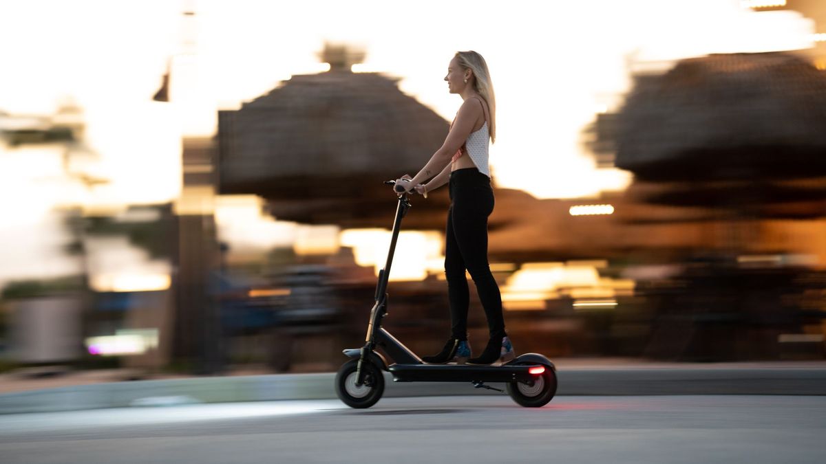 Woman enjoying an evening ride on an electric scooter with motion blur capturing speed and excitement