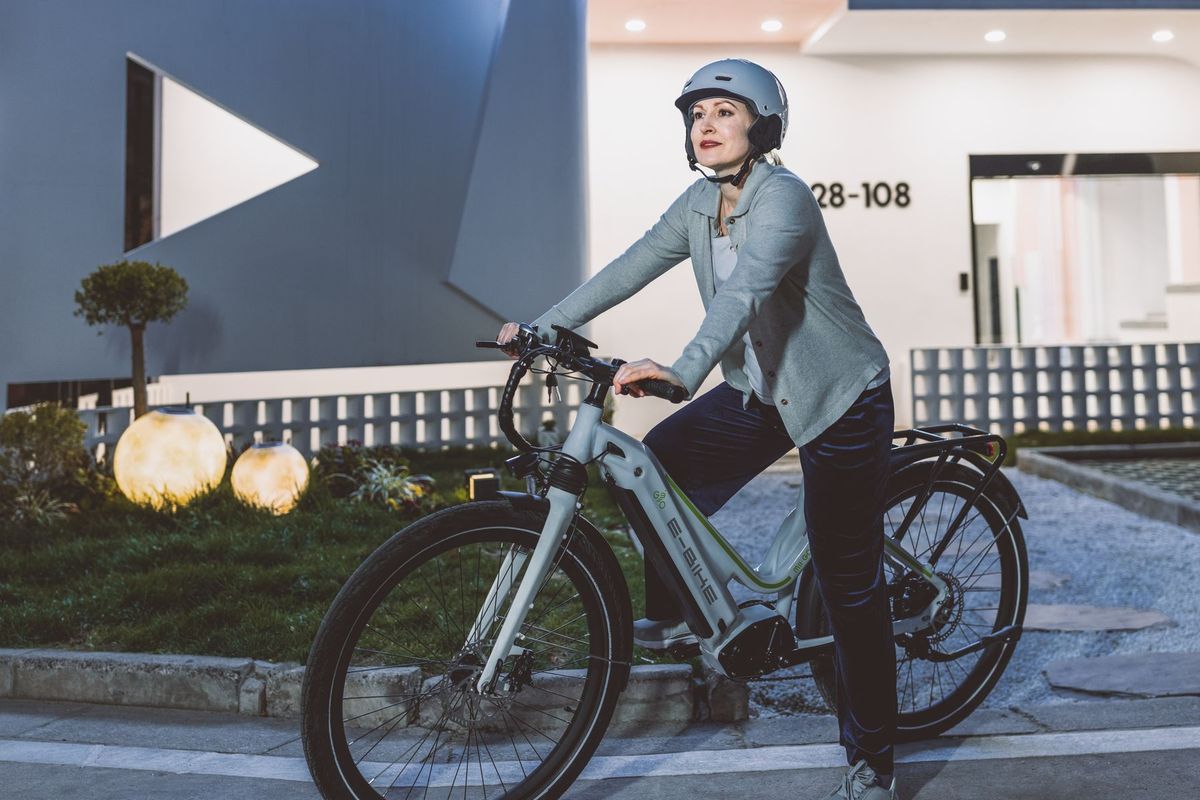 Woman in helmet riding electric bicycle in urban setting during the day