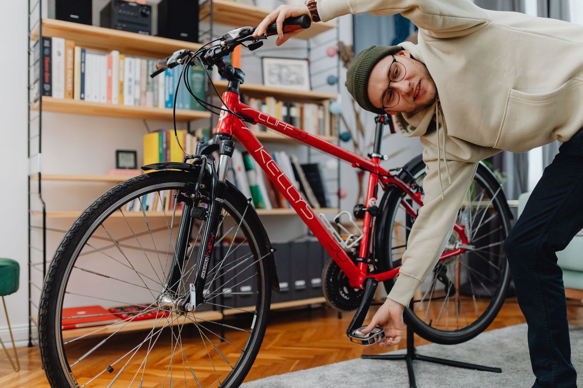 Young adult adjusting a bicycle pedal indoors